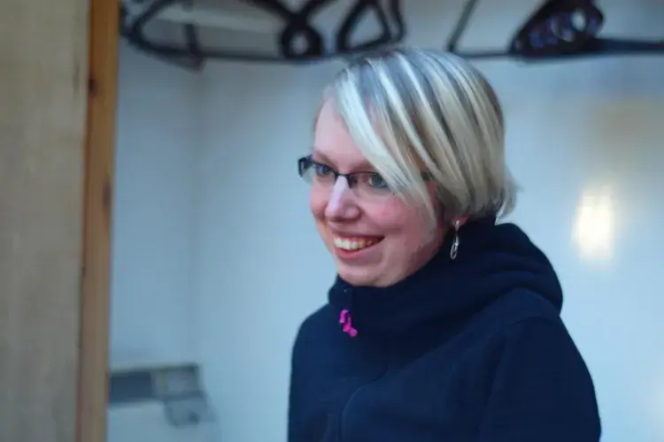 A lab member wearing ski jacket indoors, smiling