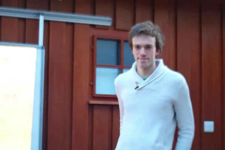 A lab member stands outside a chalet in a winter jumper