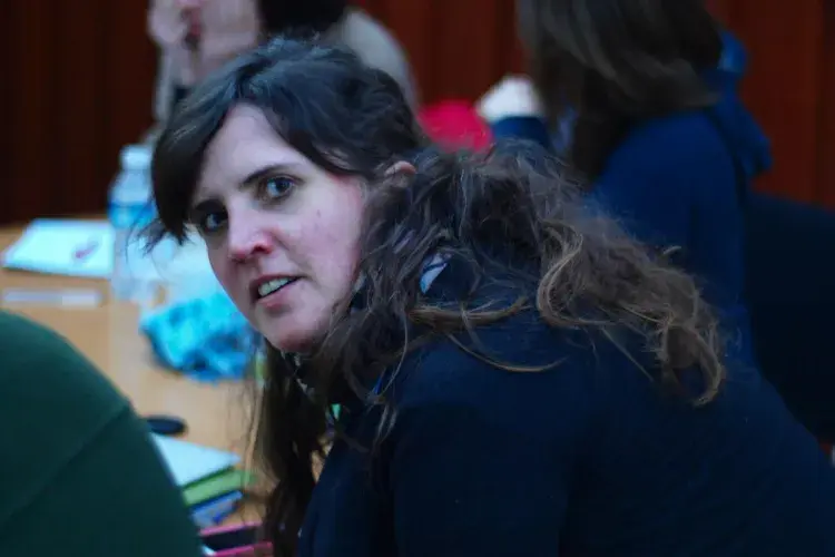 A lab member, sat at a table with other group members, turns to look at the camera