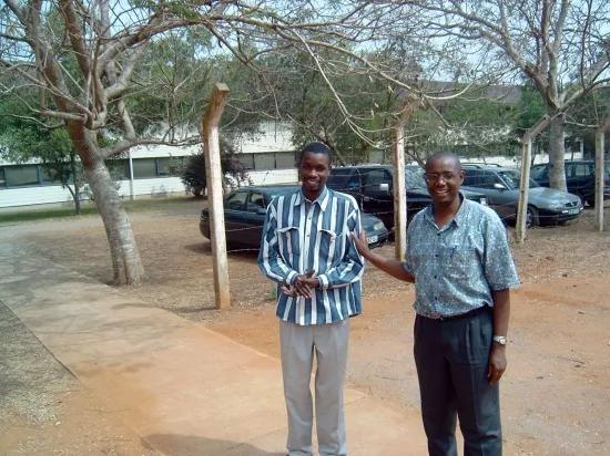 A young man and an older man standing outside and posing for a photo.