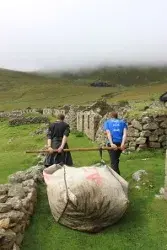 Two field workers hauling a large sack.