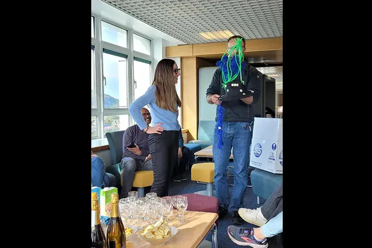 Lorenza is presented with a black hat decorated in green and blue cell structure at viva celebration