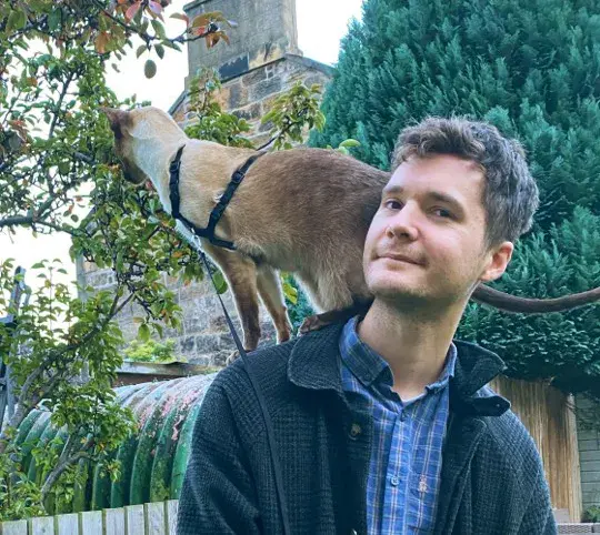 Photo of Thomas Davies in a garden with a cat on his shoulder