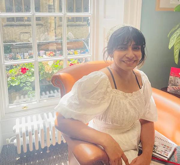 Photo of Ardra Suresh sitting in an armchair in front of a window