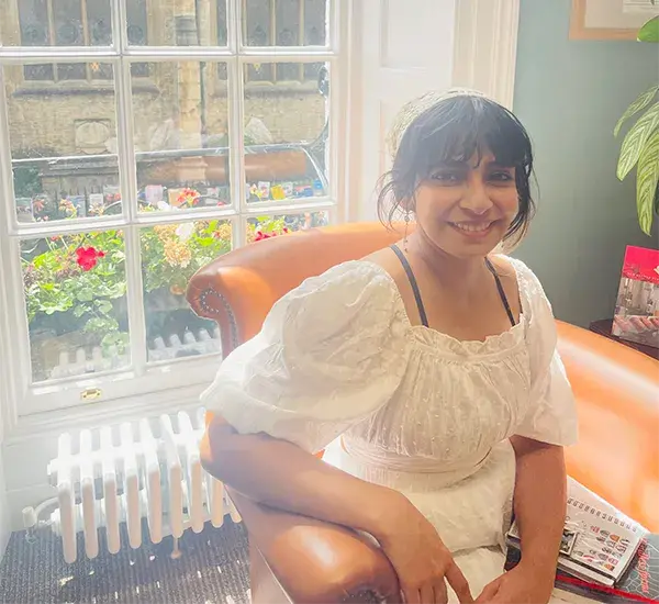 Photo of Ardra Suresh sitting in an armchair in front of a window