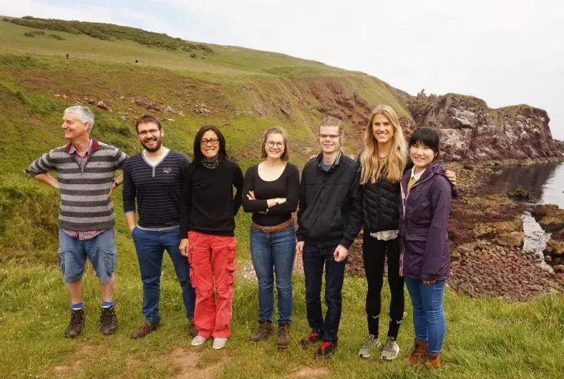 Photo of the lab group members lined up before the seashore