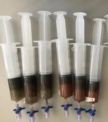 Photo of 5 partially full syriinges with dark green and brown sediment.