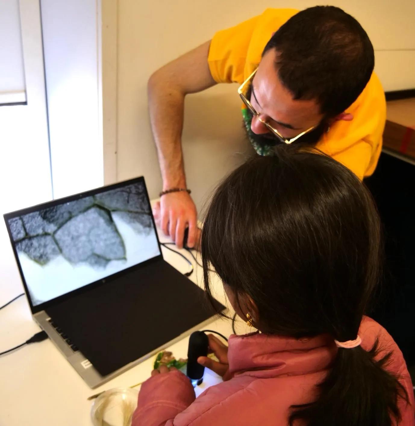 A child uses a mini handheld microscope to look at cell shapes.
