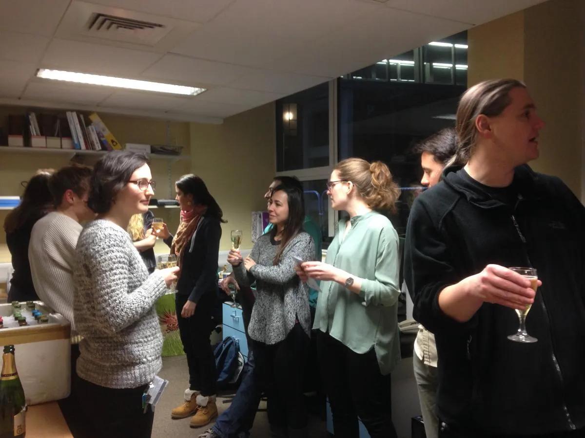 Photo of lab members in an office standing chatting