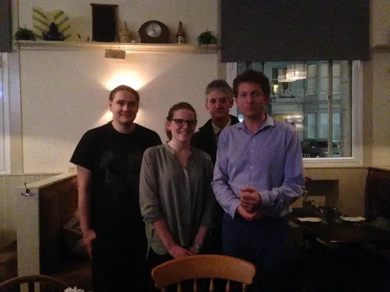 Photo of Loise with Gerben and 2 in a room in front of a shelf and a window