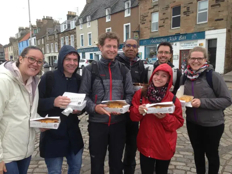 Photo of the lab group members holding fish and chip cartons in a town with cobbled streets