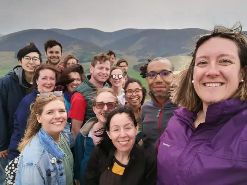 Photo of Spoeal and van Ooijen lab members posing for a photo in front of a hilly landscape