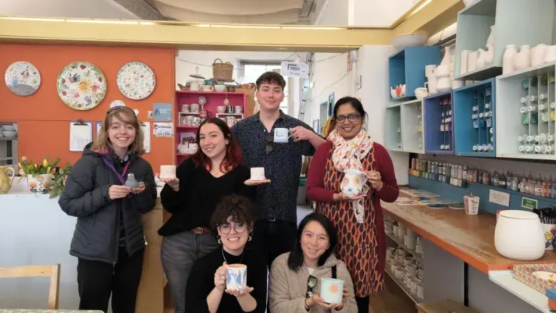 Photo from a lab social pottery painting day out, showing group members with their painted pottery