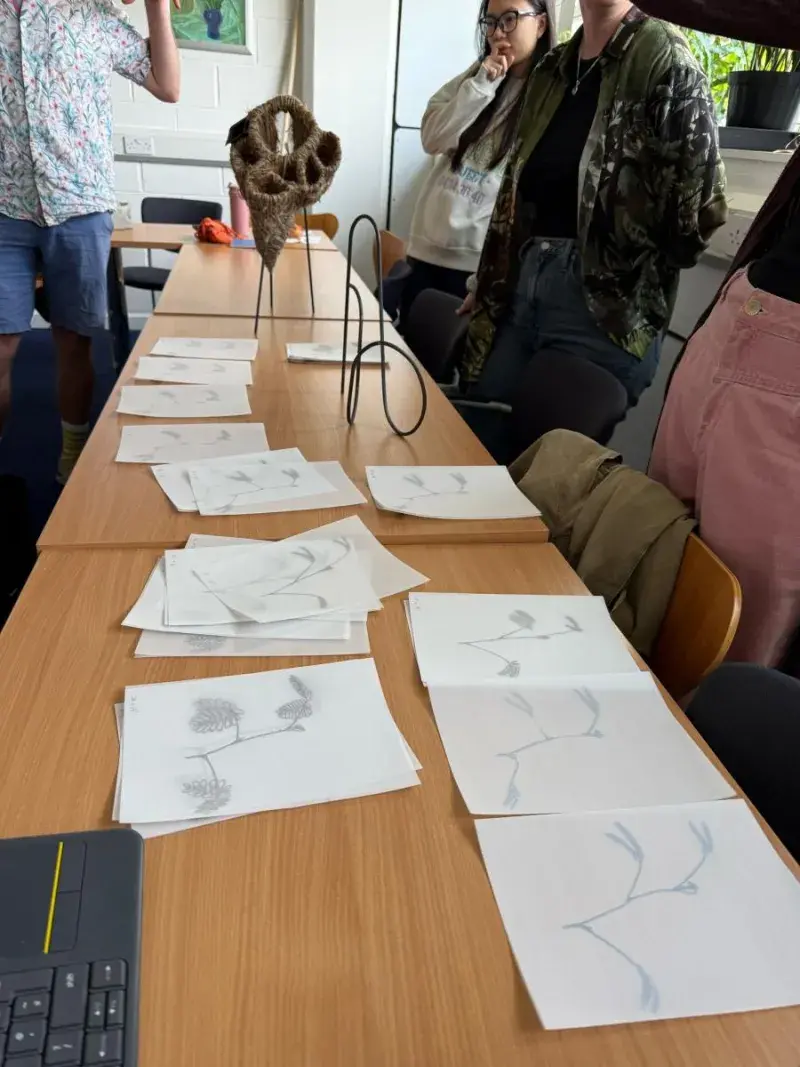 PhD student Irene's circadian-inspired sculptures on a long table beside sketches of the circle with people standing close by.