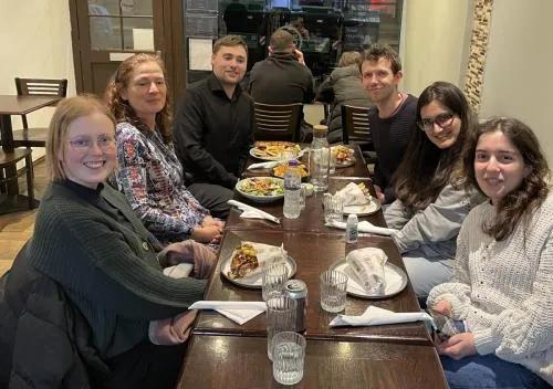 Photo of the lab group members sitting around a table in a restaurant with plates of food in front of them