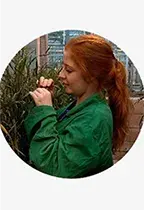 A young woman with red hair works with barley in a greenhouse