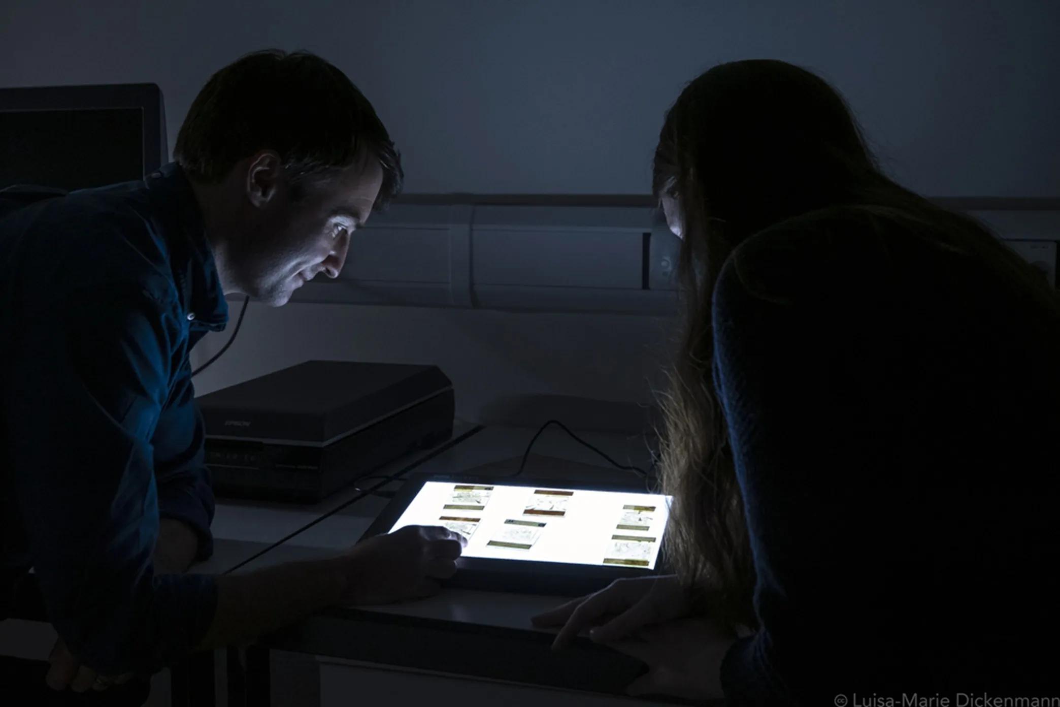 Dr Sandy Hetherington looks at slides on a light box with a student