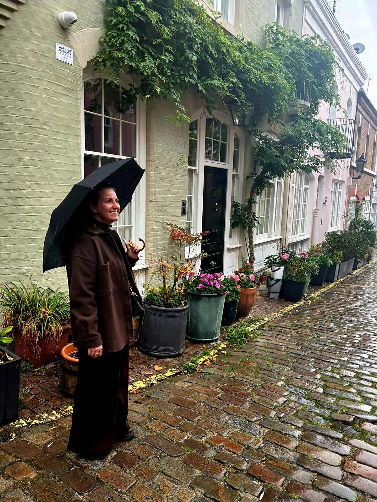 Image of Taylor Dyba under an umbrella standing next to colourful houses