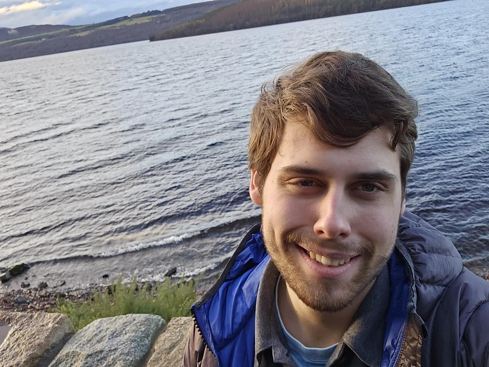 Image of Tymek Pacamaj in front of a sunny loch