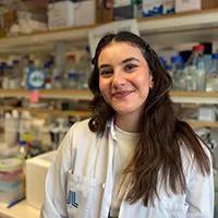 Photo of Irsil Gunes in the lab weaing white lab coat