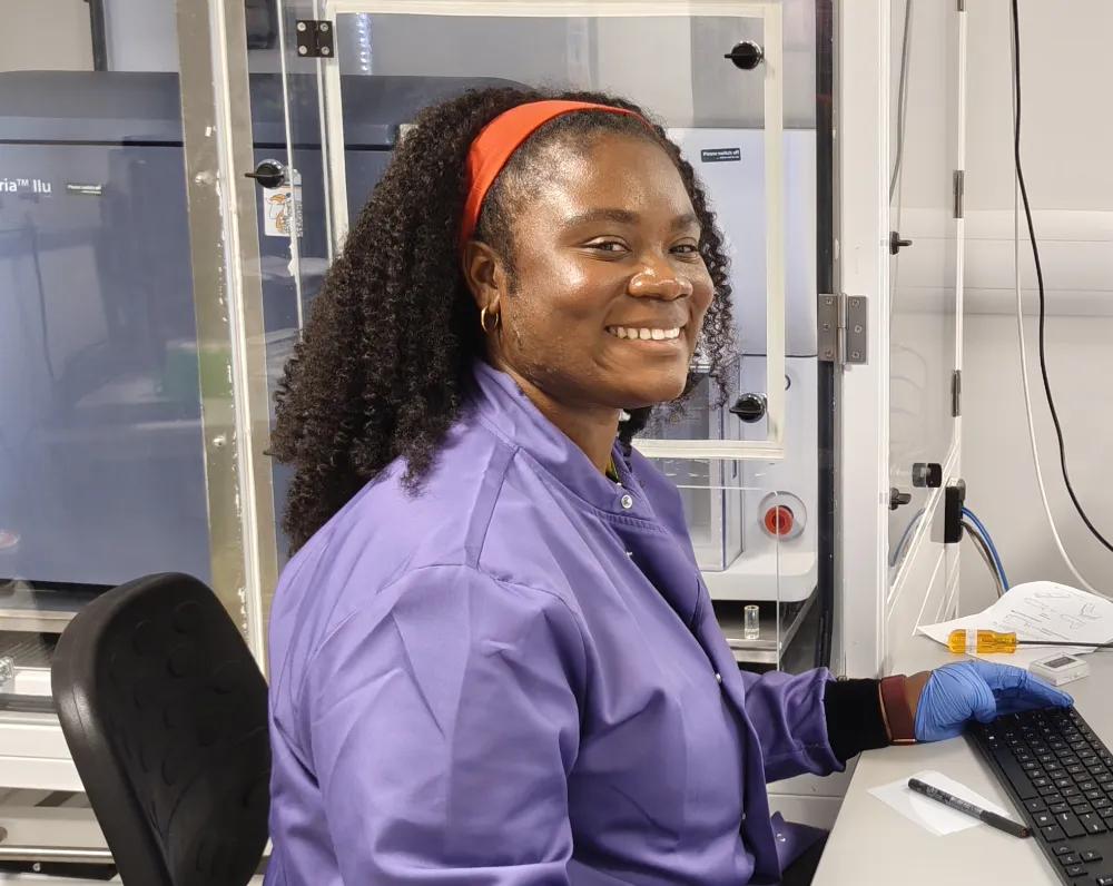 Rita dapaah sitting in front of a FACS ARIA cell sorter