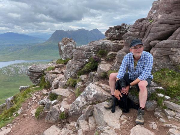 Photo of Kevin Hardwick on a mountain peak with his dog