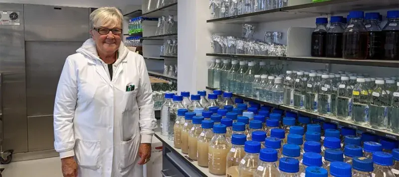 Photo of media prep staff member together with prepared media in bottles