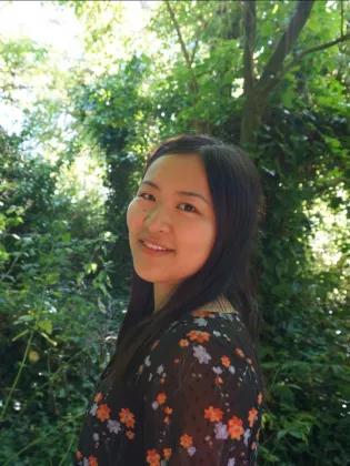 Headshot of Maxine smiling with trees in the background.