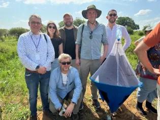 Matthews research group standing outside holding a tsetse fly trap.