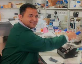 Dr. Abdelrahman Zaky working in a lab and smiling.