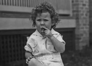 Black and white image of a small child smoking a cigar.