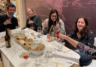 Photo of the lab group members sitting around a table in a restaurant with lots of wine glasses, and a cheese platter on it.