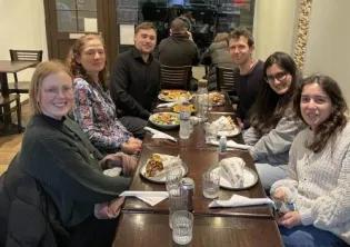 Photo of the lab group members sitting around a table in a restaurant with plates of food in front of them