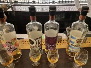 Photo of a bar with 4 different bottles of whisky on it and with a glass of each in front