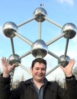 Photo of Scott Cockroft in front of a large metal sculpture of molecules with a French flag on top