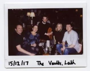 Photo of the lab group member, seated and gathered around a table in the vaults, Leith