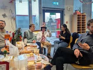 Photo of the lab group members sitting on chairs around tables with food and drink on them