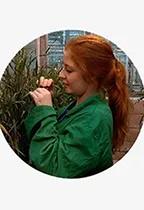 A young woman with red hair works with barley in a greenhouse