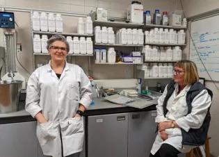 Two media and wash-up staff members wearing lab coats in office