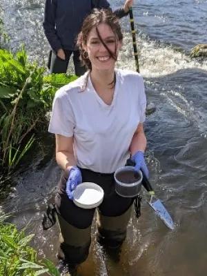 Photo of Hanna Peach holding samples whilst stading in a river