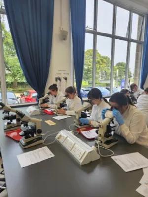Students in a lab wearing white coats working at benches 