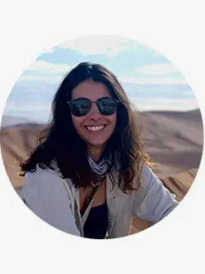 A young woman with brown hair, wearing sunglasses, smiling