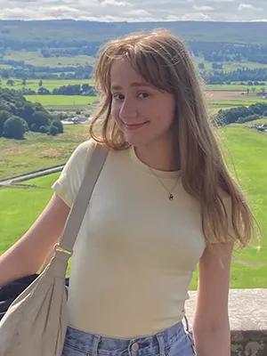 Photo of Aniela standing in front of a vast green landscape