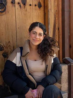 Photo of Nitara sitting in front of a large wooden door