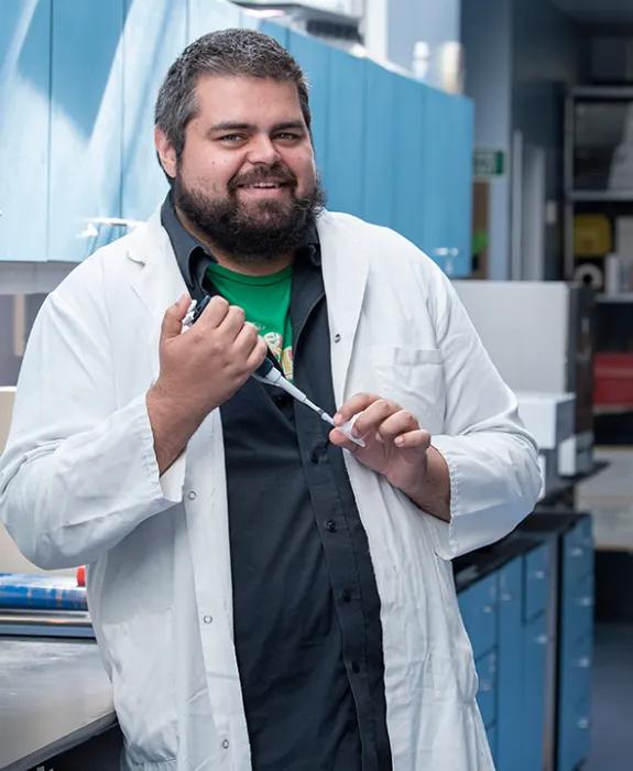 Photo of Frank in the lab wearing a white lab coat