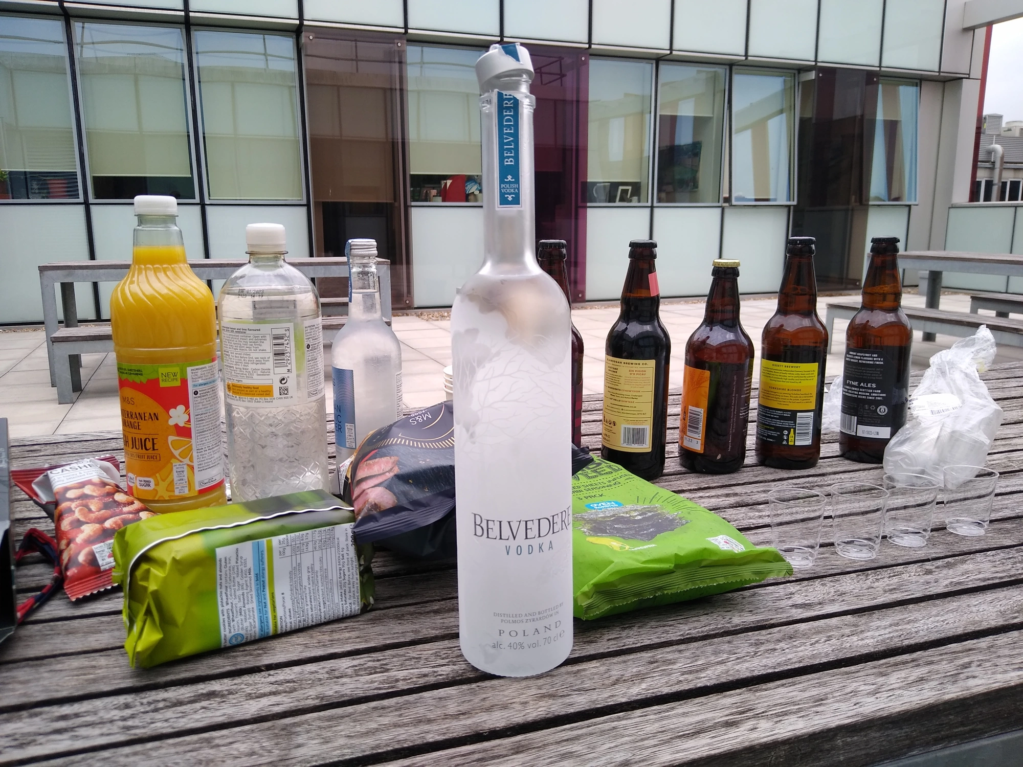 Picnic table outside a building with various bottles on it