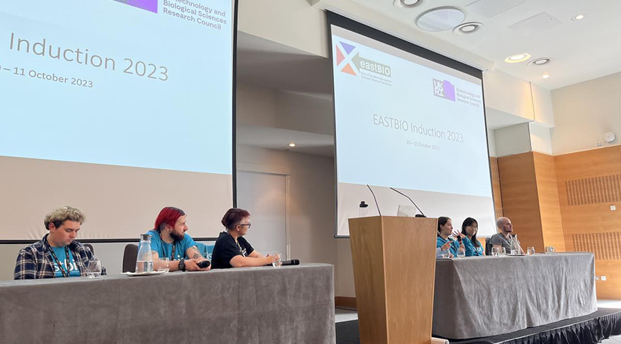 Six students and supervisors sit in front of screens at the programme induction 2023