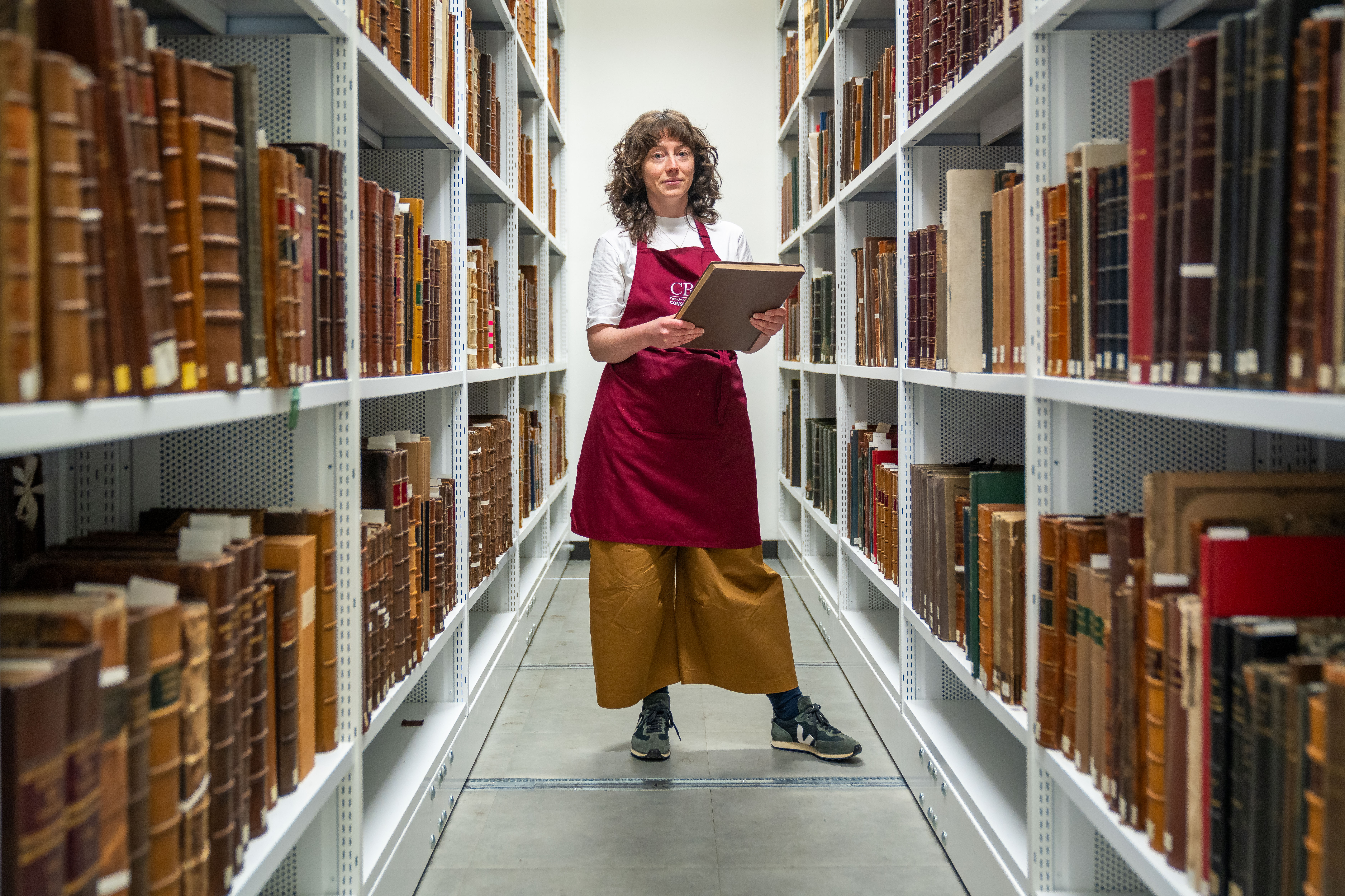 Staff member working with folios in archival stacks