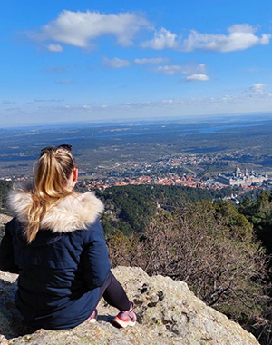 Photo of Abigail sitting taking in a view from a height overlooking townd and countryside