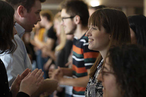 Rows of students stand opposite one another and talk